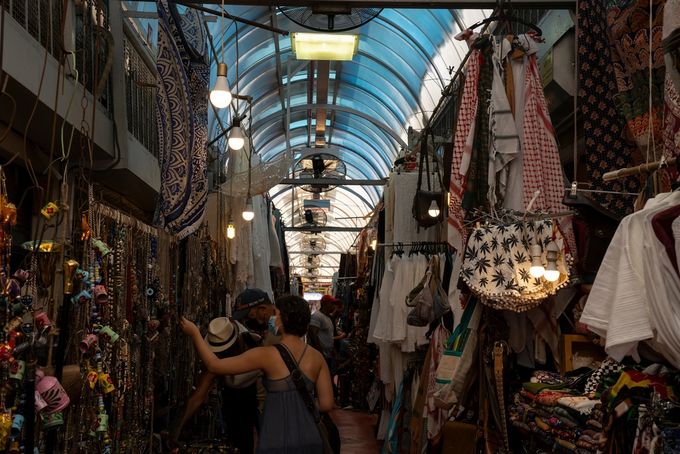 Tourists browsing market with many different items for sale